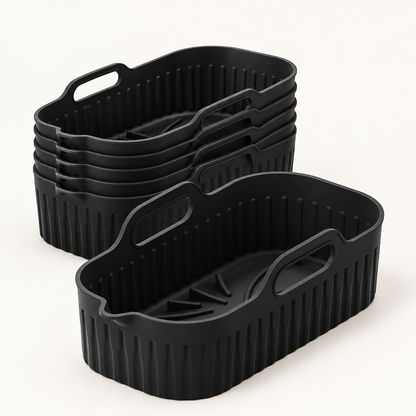 Pack de 6 bandejas rectangulares de silicona negras Manacor para freidora de aire, de 8 por 20 por 12 cm, sobre una superficie clara